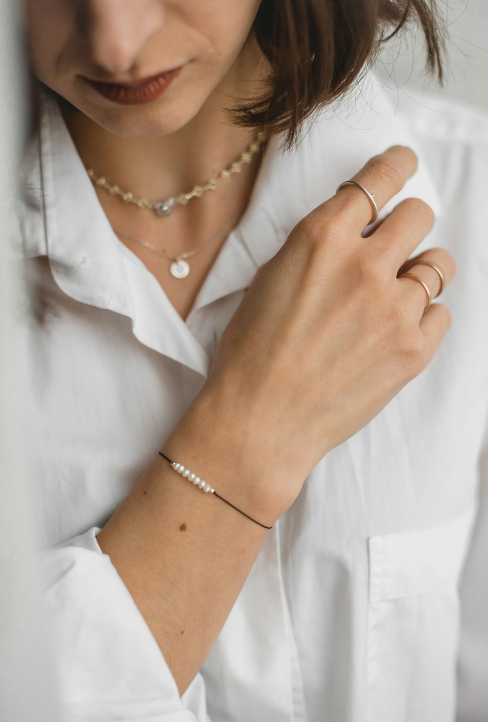 woman in white button up shirt wearing gold bracelet