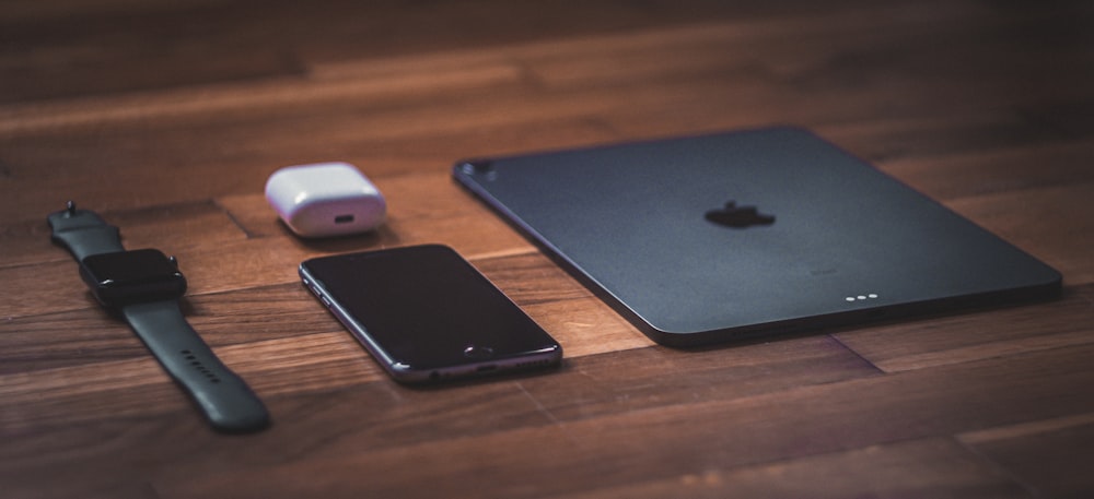 Schwarzes iPad neben weißer Apple Magic Mouse auf braunem Holztisch