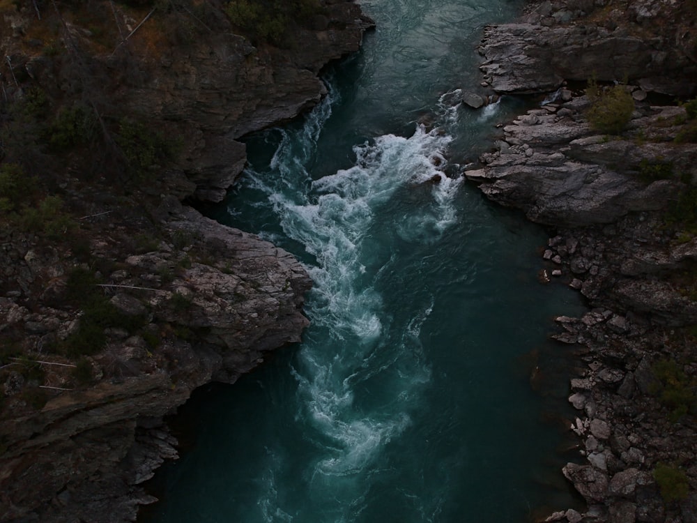 river between brown and green rock formation during daytime