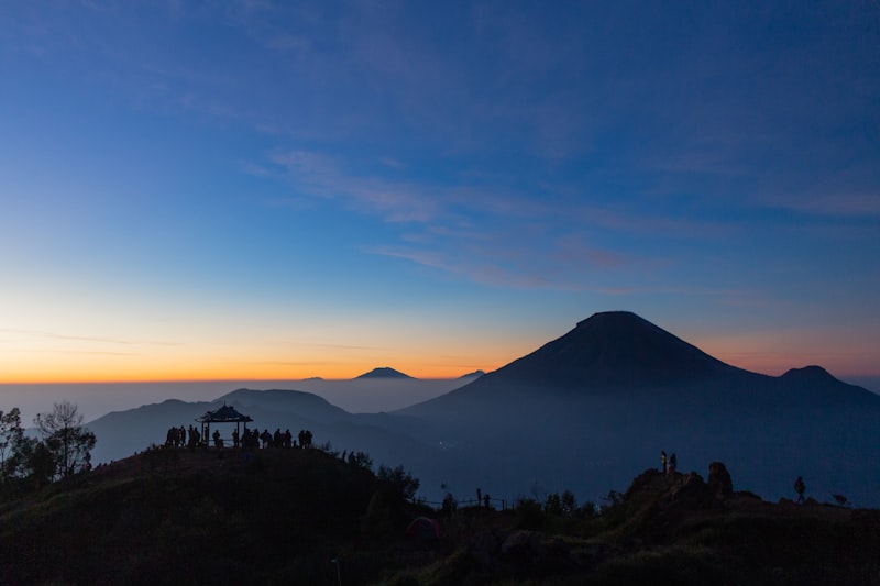 Siluet pendaki tektok di puncak gunung saat sunset