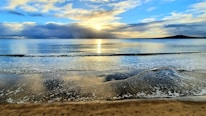 A serene beach sunset with calm waves and empty shore.
