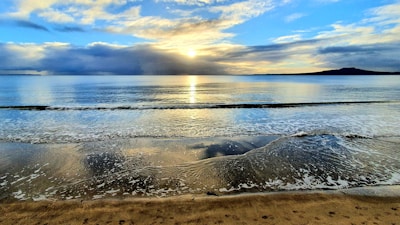 A serene beach sunset with calm waves and empty shore.
