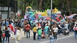 Colorful installations and cultural exhibits lining a lively street filled with curious attendees.