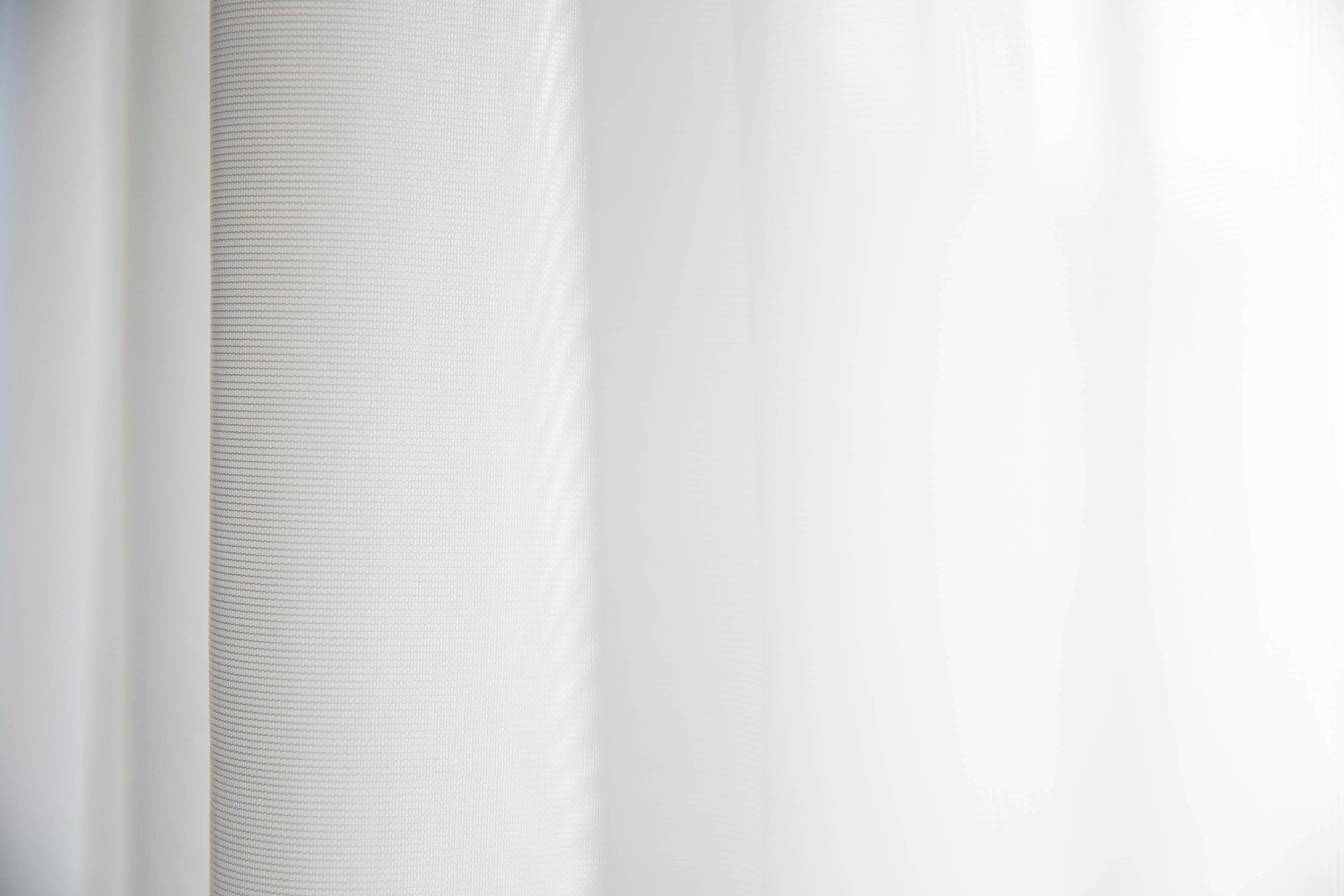 Flowing white linen sheer curtains catching natural light in an airy, minimalist European interior with soft ethereal glow