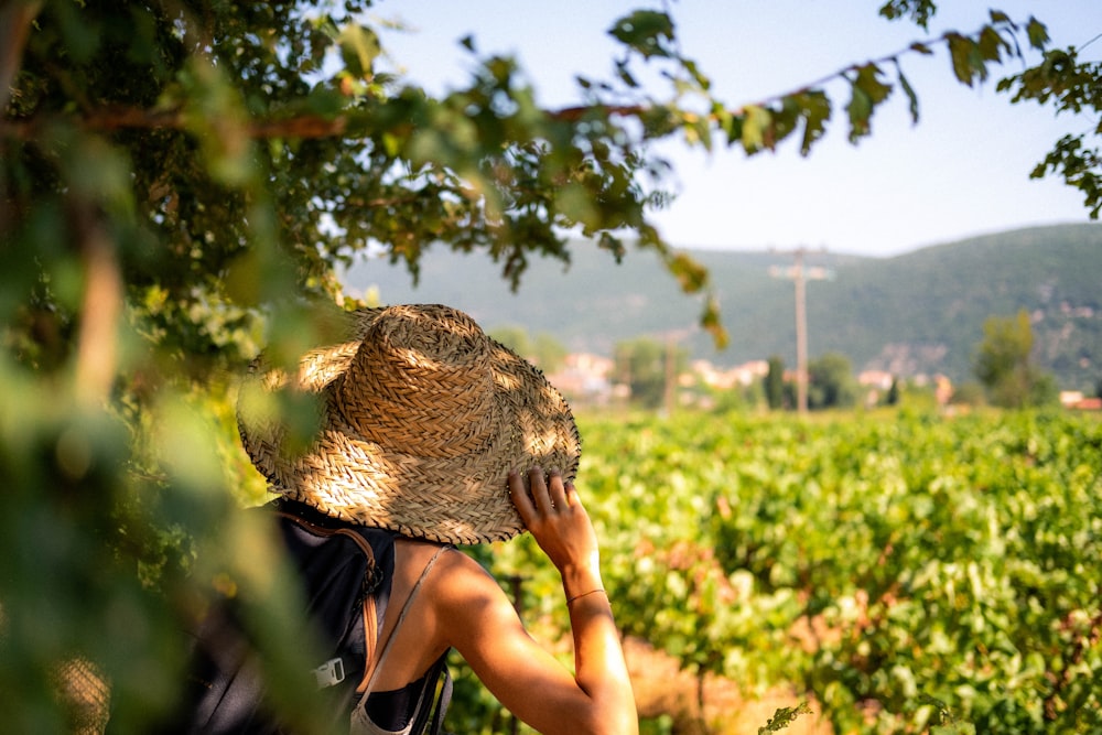 woman in black shirt and brown sun hat standing under green tree during daytime