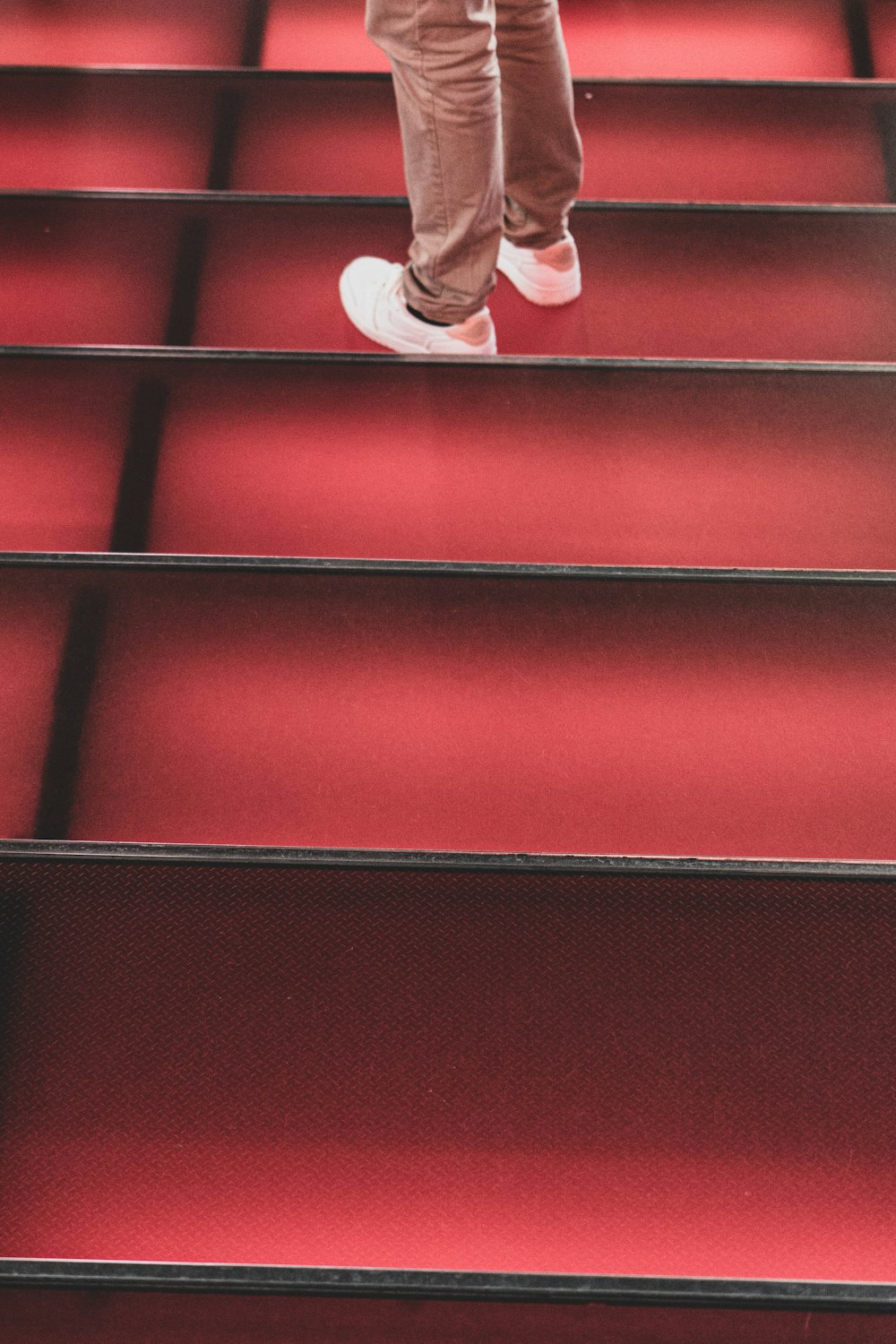 person in white sneakers sitting on red and black floor