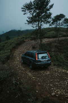 A Jetour SUV climbing a rocky trail surrounded by lush forest.
