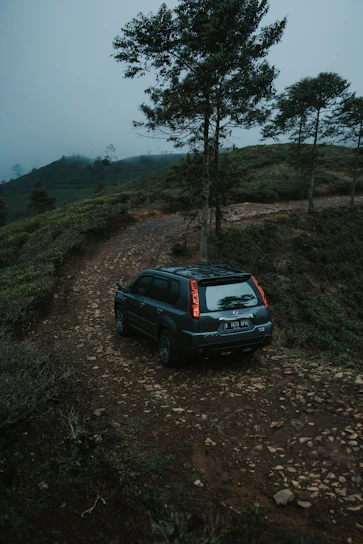 A rugged black SUV driving through a forest trail