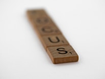 Wooden Scrabble tiles arranged to spell the word 'FOCUS' on a plain background. The tiles get progressively blurrier towards the top, emphasizing the foreground tiles.