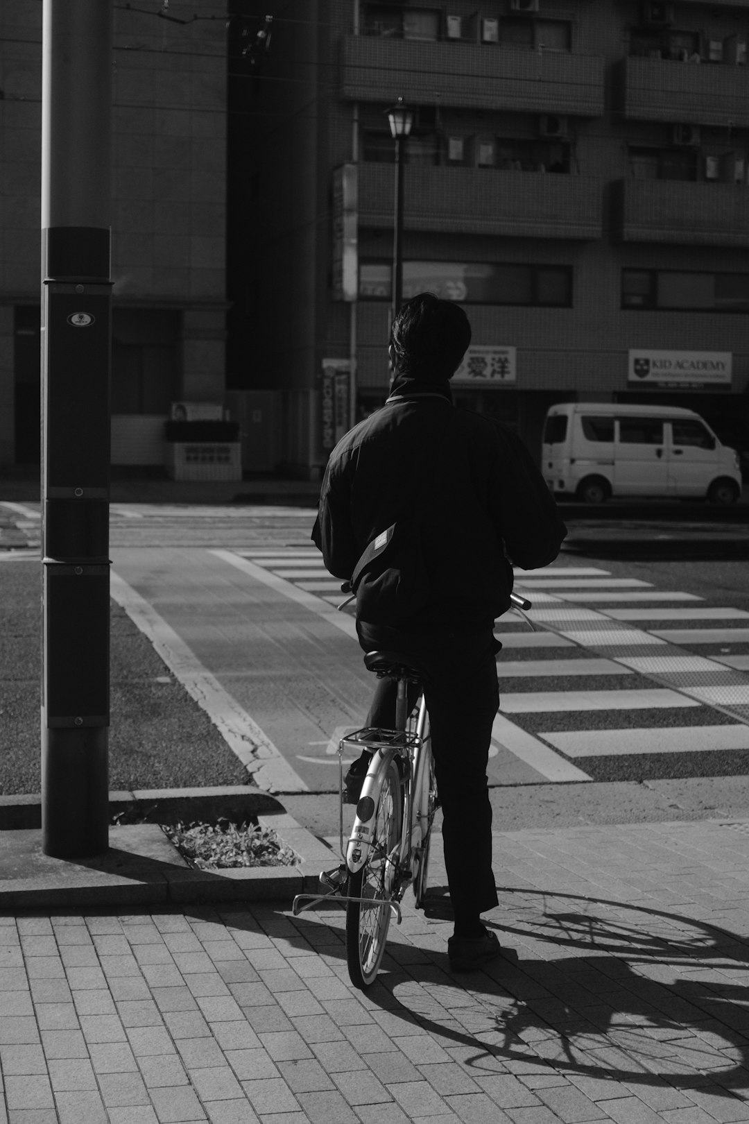 man in black jacket riding bicycle on pedestrian lane in grayscale photography