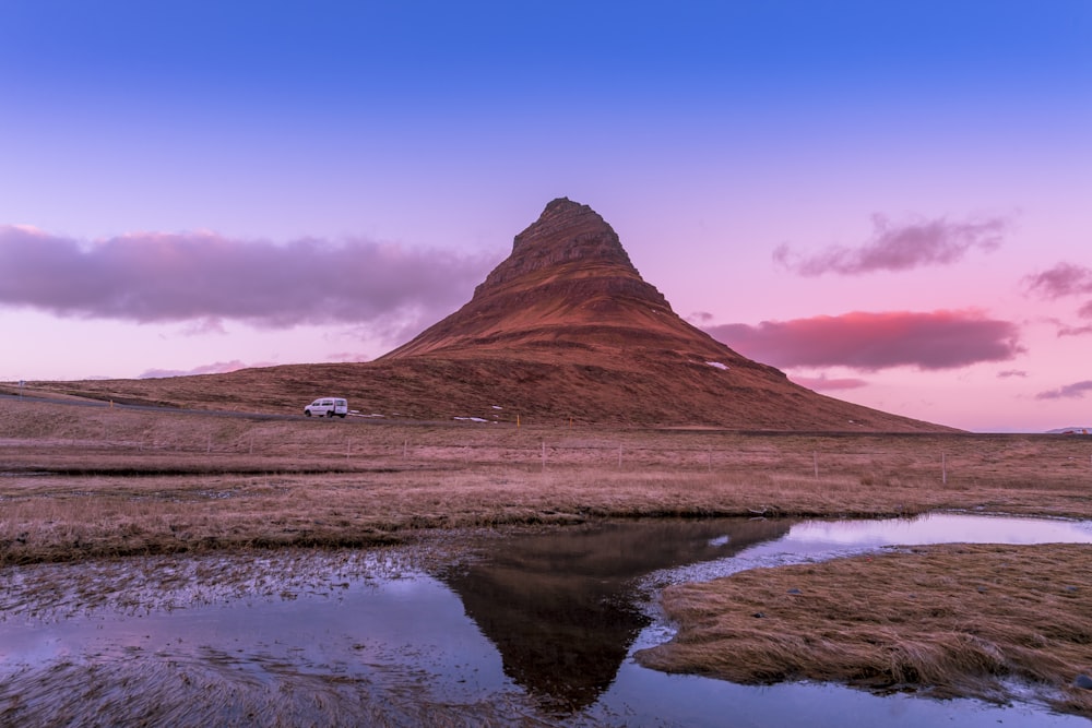 brown mountain near body of water during daytime