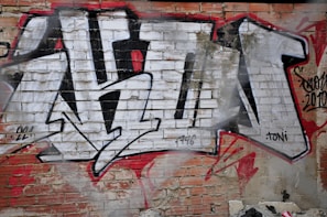A bold graphic detail of youngka's logo spray-painted on a worn brick wall.