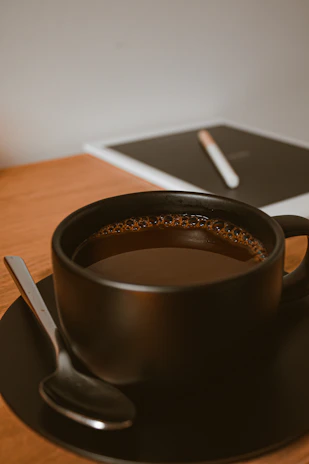 A steaming cup of black coffee beside a tablet showing an online interview preparation course.