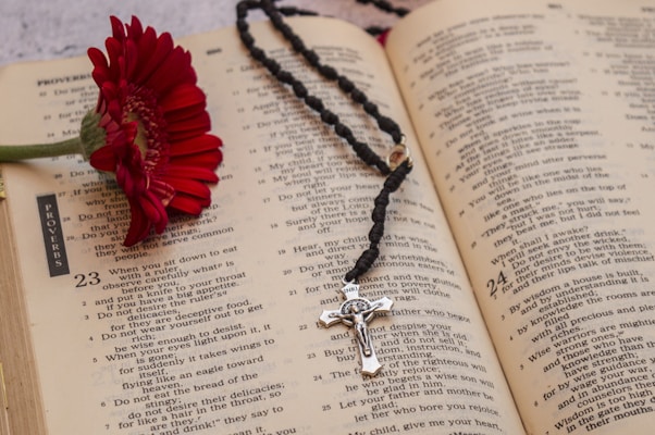 Close-up of a beautiful rosary bracelet resting on an open prayer book with spring flowers nearby.