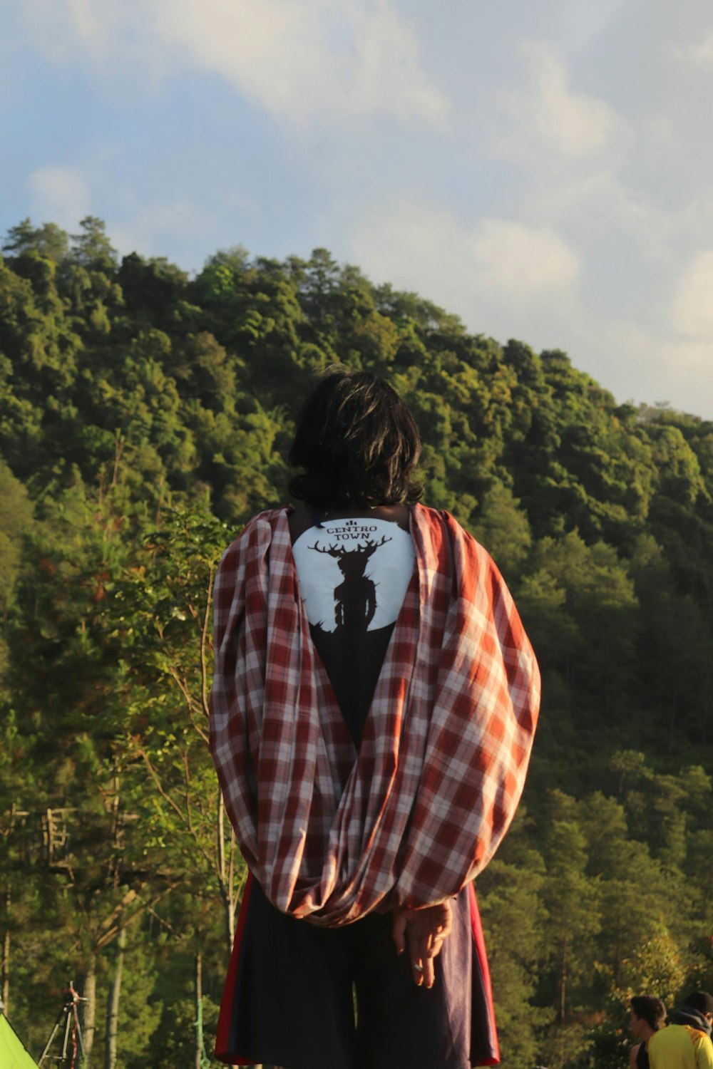 woman in red white and black plaid jacket standing on mountain during daytime