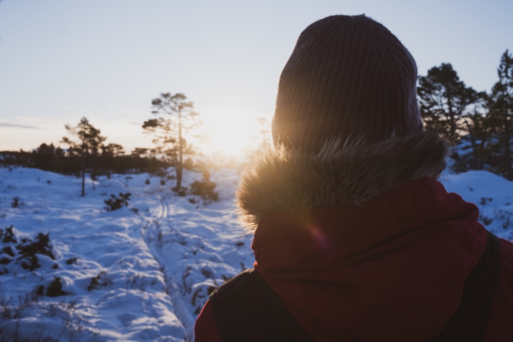 person in black and red hoodie standing on snow covered ground during daytime