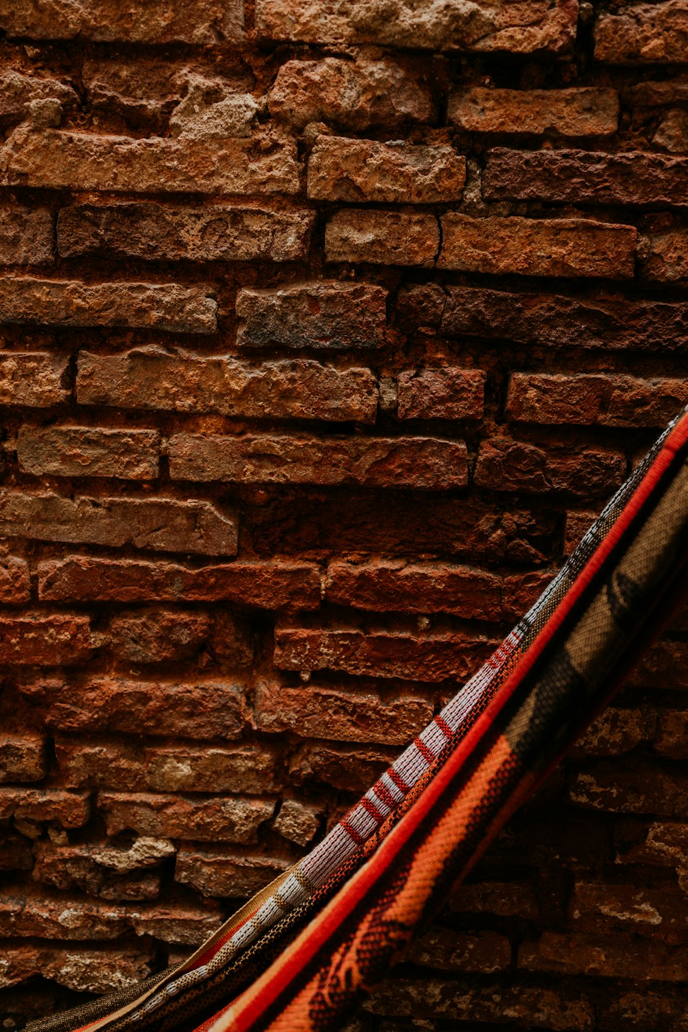 Guitarra eléctrica roja y negra apoyada en una pared de ladrillo marrón