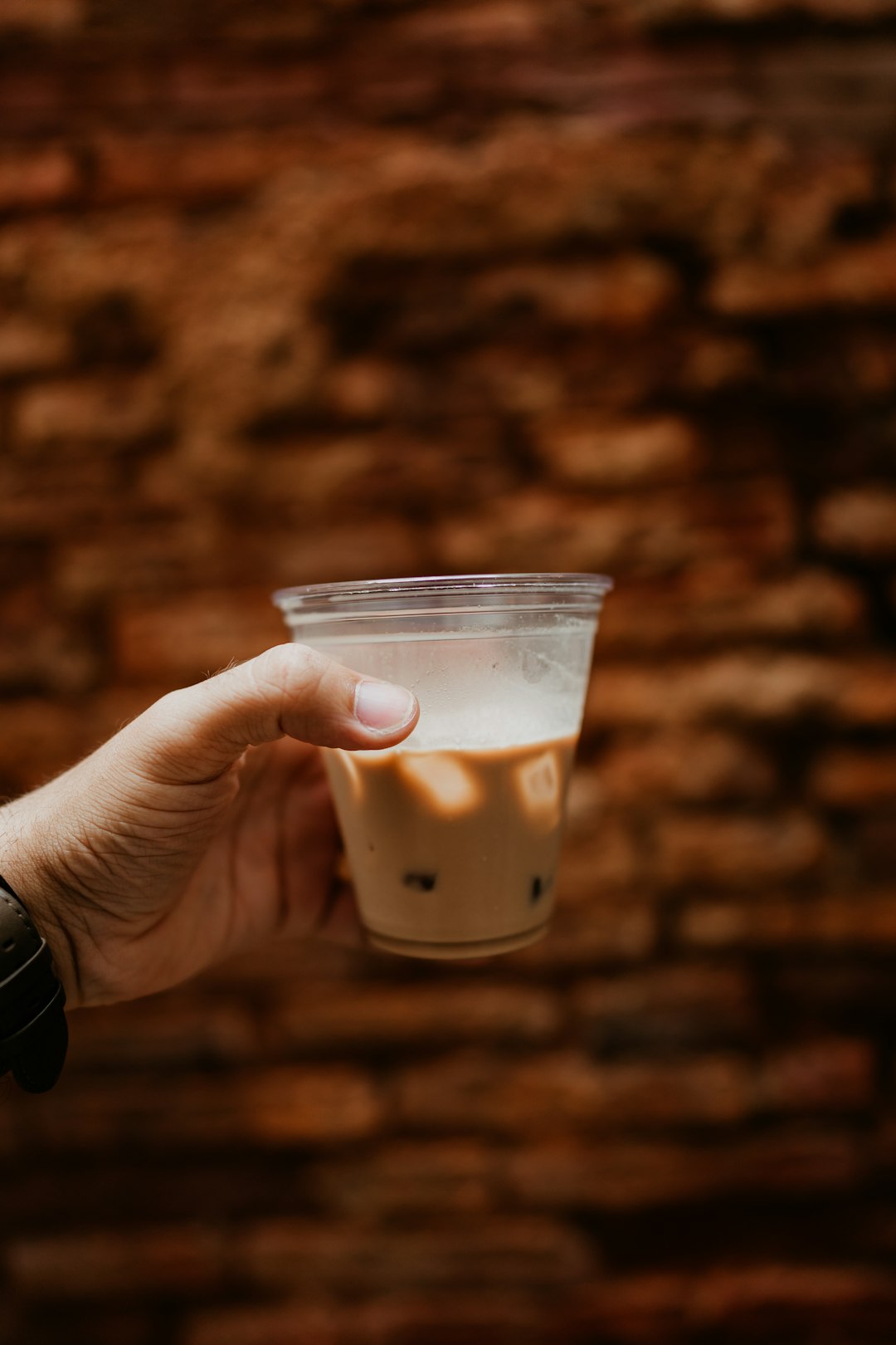 person holding clear plastic cup with white liquid