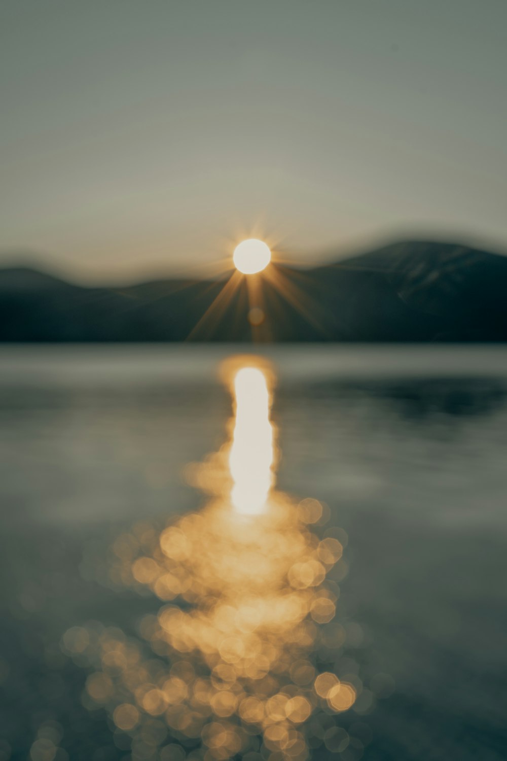 sole che tramonta sulle montagne e sullo specchio d'acqua