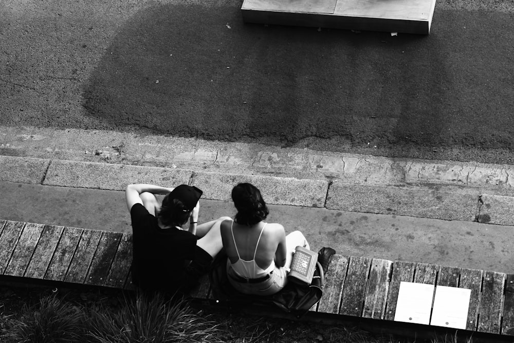 grayscale photo of 2 women sitting on concrete bench