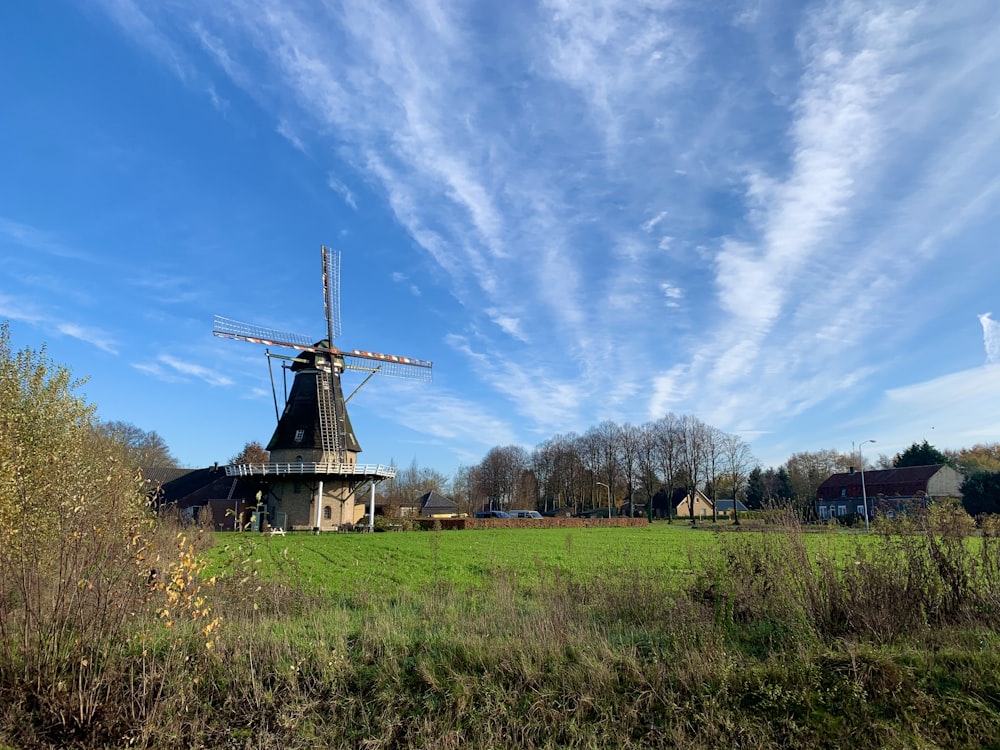 brown windmill on green grass field under blue sky during daytime