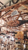 A wooden structure featuring shelves and hanging elements displays various handmade pottery and ceramics. The setup includes vibrant ceramic bowls, plates, and ornaments, with some pieces hanging. Natural lighting adds warmth to the scene.