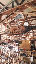 A wooden structure featuring shelves and hanging elements displays various handmade pottery and ceramics. The setup includes vibrant ceramic bowls, plates, and ornaments, with some pieces hanging. Natural lighting adds warmth to the scene.