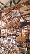 A wooden structure featuring shelves and hanging elements displays various handmade pottery and ceramics. The setup includes vibrant ceramic bowls, plates, and ornaments, with some pieces hanging. Natural lighting adds warmth to the scene.