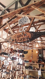 A wooden structure featuring shelves and hanging elements displays various handmade pottery and ceramics. The setup includes vibrant ceramic bowls, plates, and ornaments, with some pieces hanging. Natural lighting adds warmth to the scene.