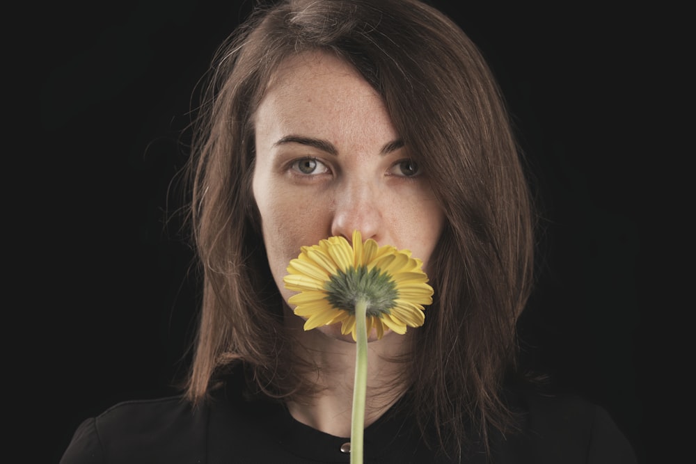 woman in black shirt holding yellow flower