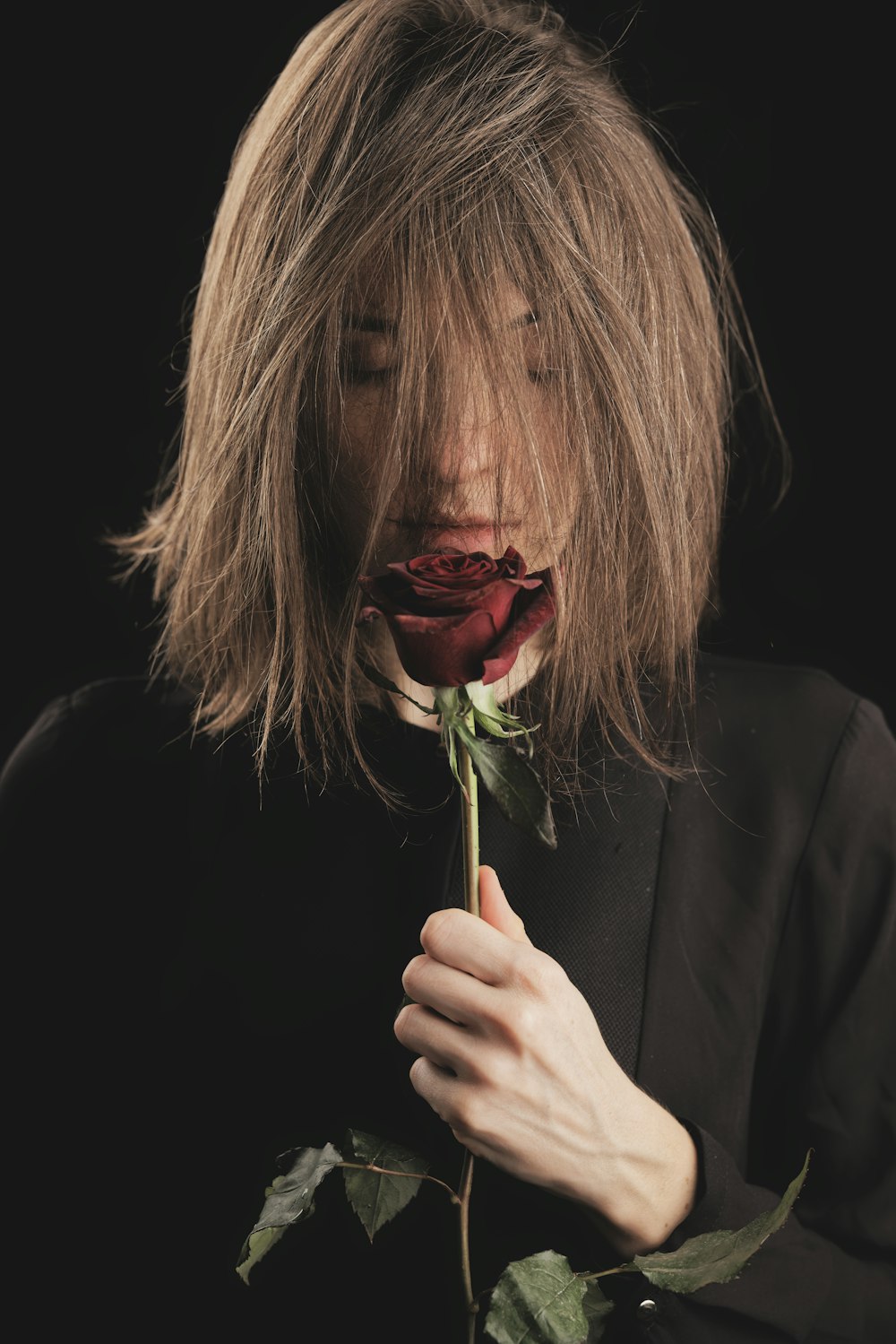 woman in black long sleeve shirt holding red rose