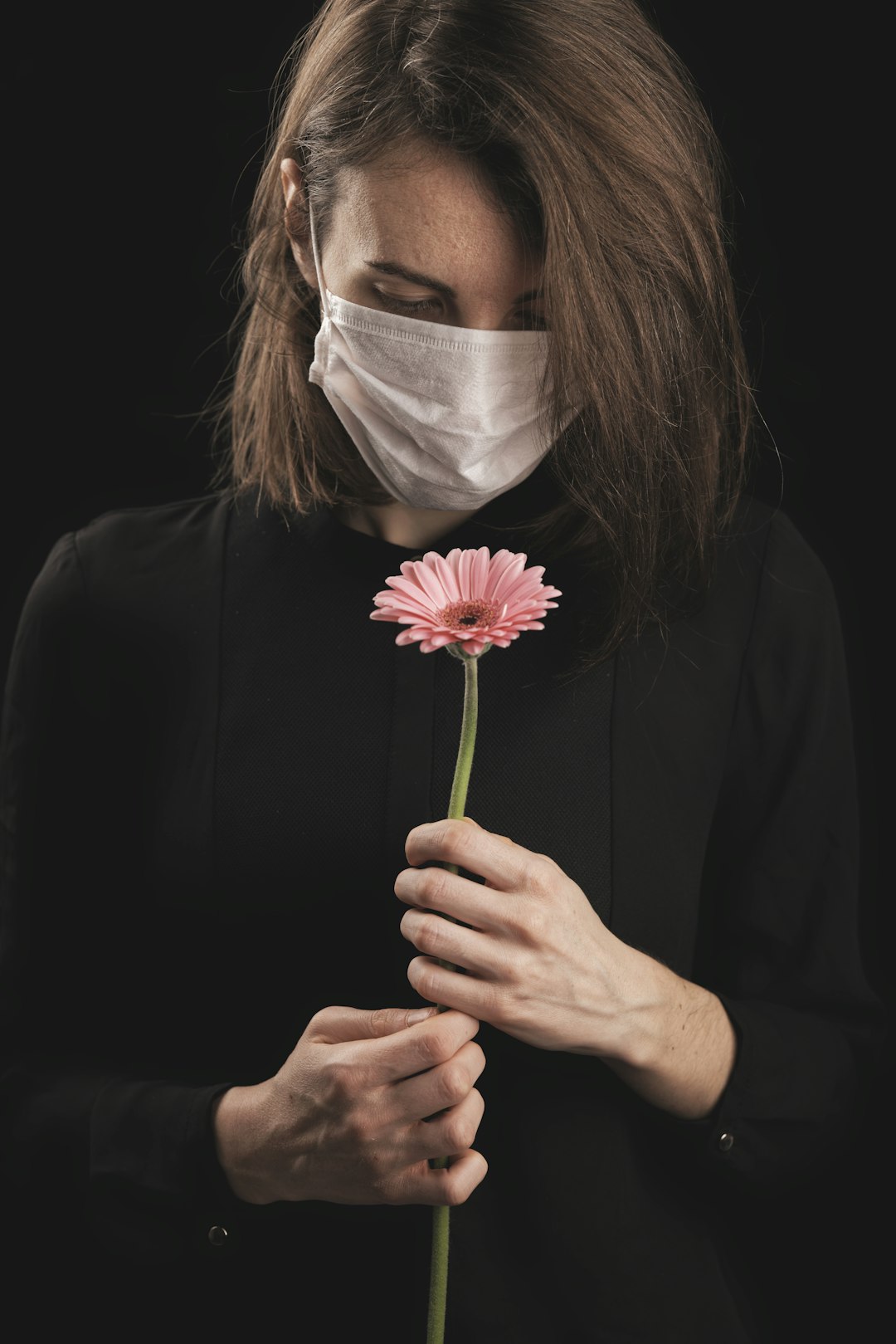 woman in black long sleeve shirt holding pink flower