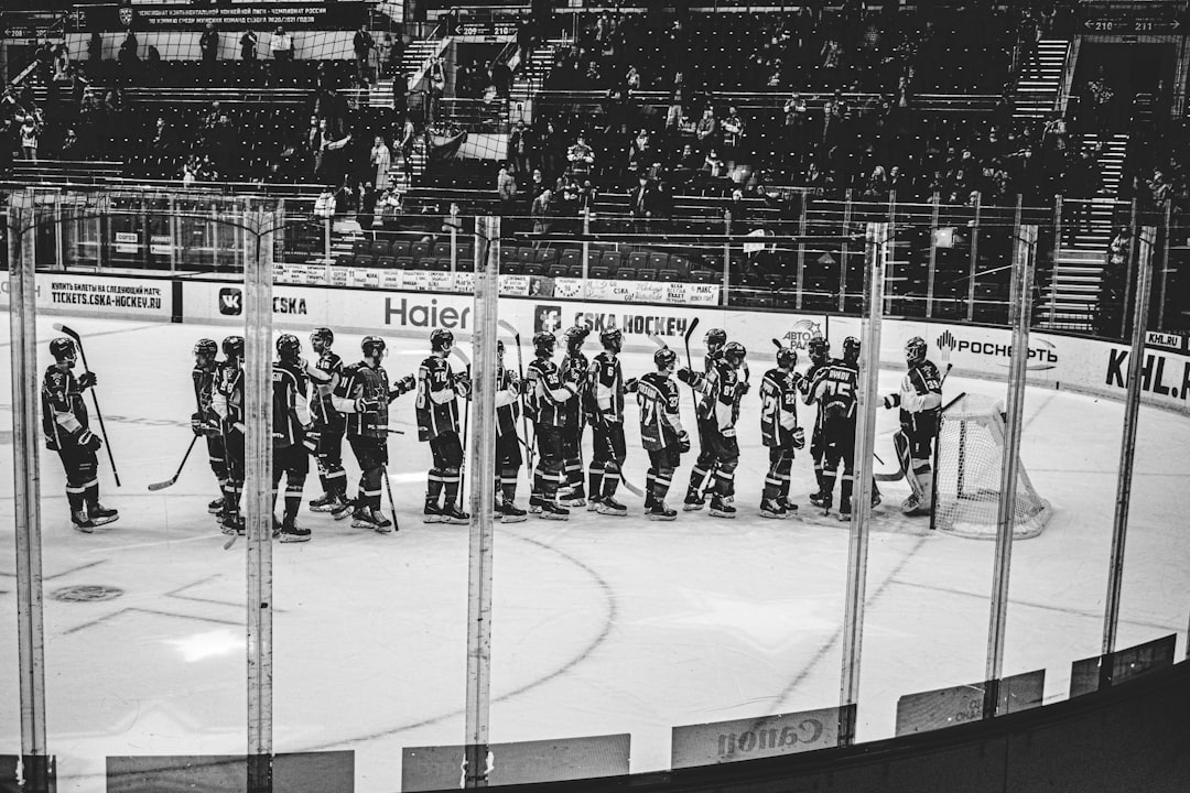 grayscale photo of people standing on ice hockey field