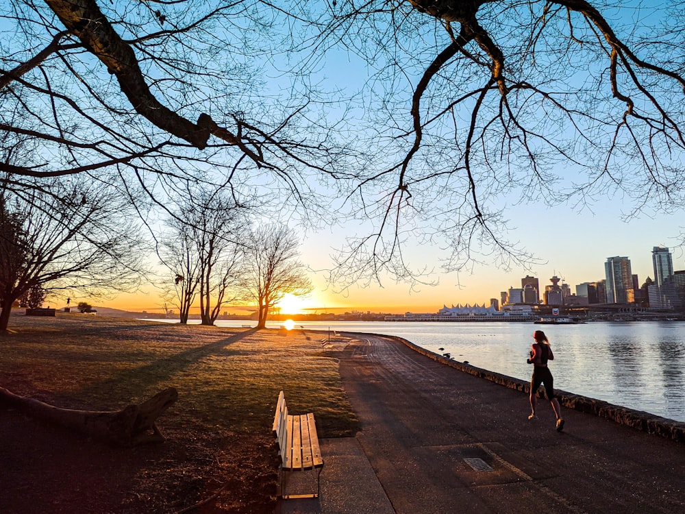 man and woman walking on sidewalk near body of water during sunset