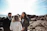 A sunlit wedding ceremony by the breakwall with close friends gathered around.