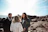 A sunlit wedding ceremony by the breakwall with close friends gathered around.