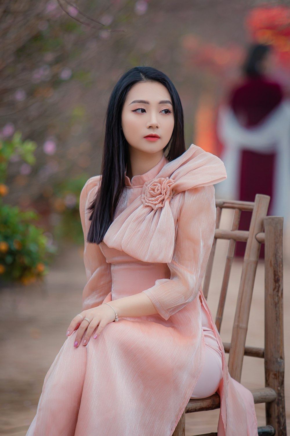 woman in pink dress sitting on brown wooden chair