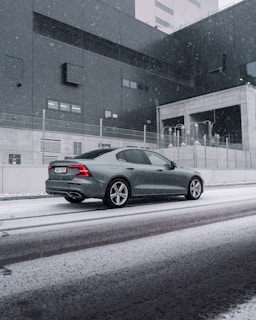 A sleek electric car parked on a snowy Finnish street at dusk