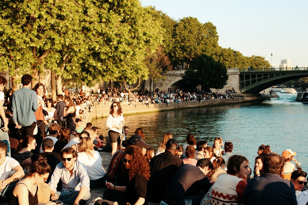 people sitting on concrete floor near body of water during daytime