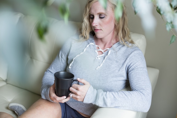 woman in gray long sleeve shirt holding black ceramic mug