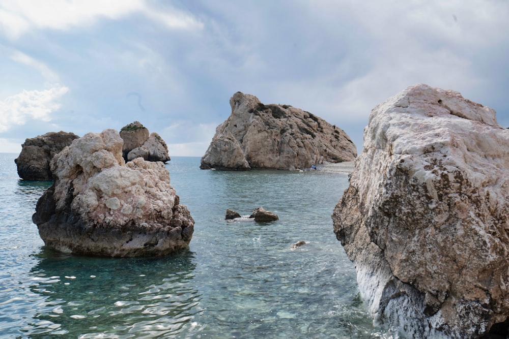 brown rock formation on sea under white clouds during daytime