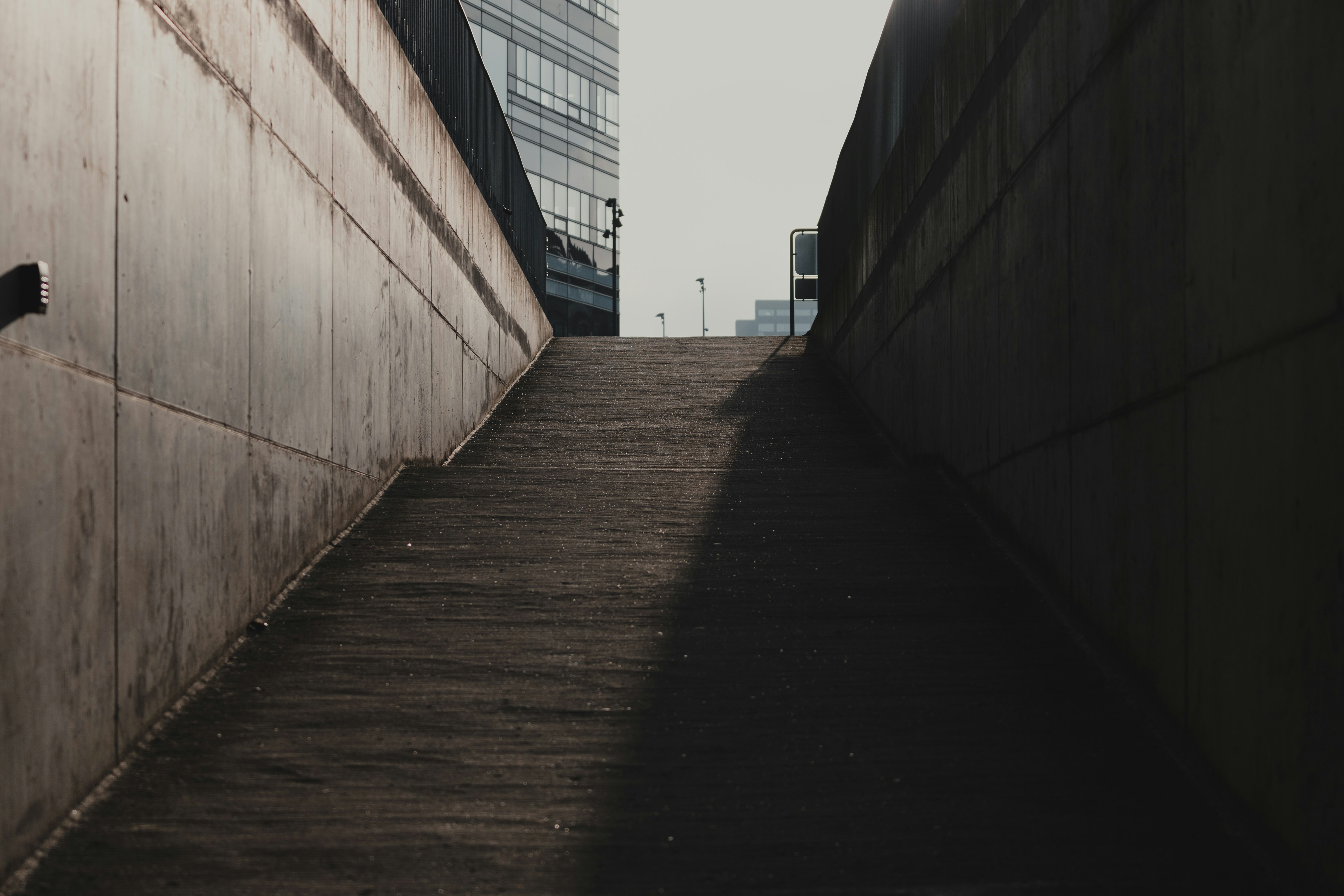 brown wooden pathway between concrete walls