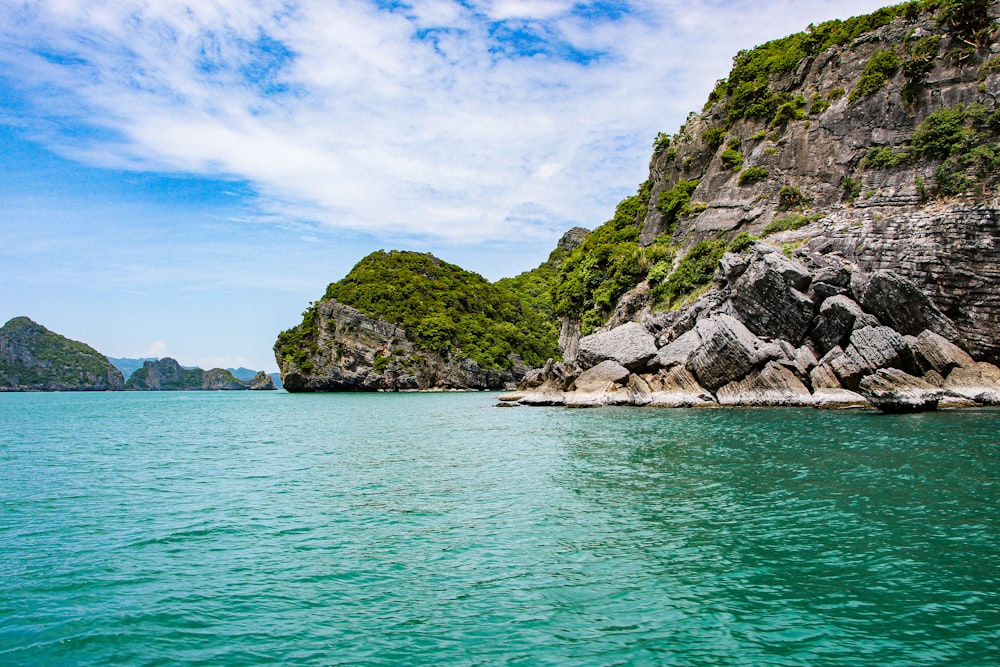 green and brown mountain beside body of water during daytime