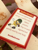 A Sun-Maid raisins package is shown with marketing text emphasizing raisins as a healthy snack. The illustration features a cartoon raisin wearing a football helmet and gloves, giving a thumbs-up gesture.