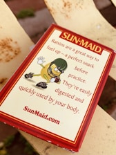 A Sun-Maid raisins package is shown with marketing text emphasizing raisins as a healthy snack. The illustration features a cartoon raisin wearing a football helmet and gloves, giving a thumbs-up gesture.