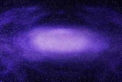 A vast, purple-hued galaxy filled with a multitude of stars spread across the dark expanse of space. The center of the galaxy is brighter, indicating dense star clusters, while the outer areas fade into a deeper purple and black, giving it a sense of depth and immensity.