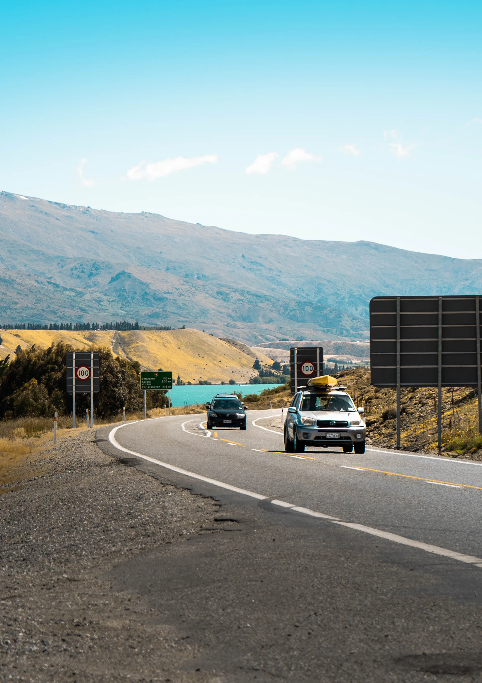 A road crosses open New Zealand country toward distant mountains