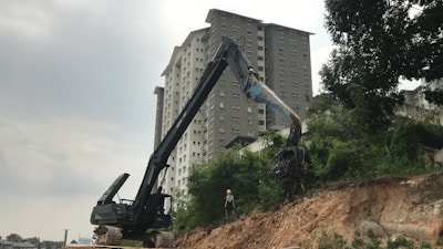 A professional excavator at work on a construction site surrounded by lush greenery.