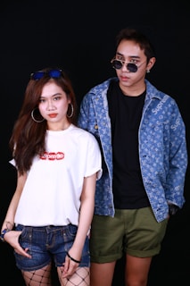 Man and woman dressed in chic, modern outfits posing against a minimalist black background