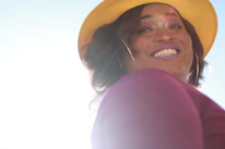 A joyful woman wearing Luna Brill earrings and necklace, smiling in natural light.